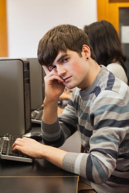 Студент, выглядящий усталым в компьютерном зале
