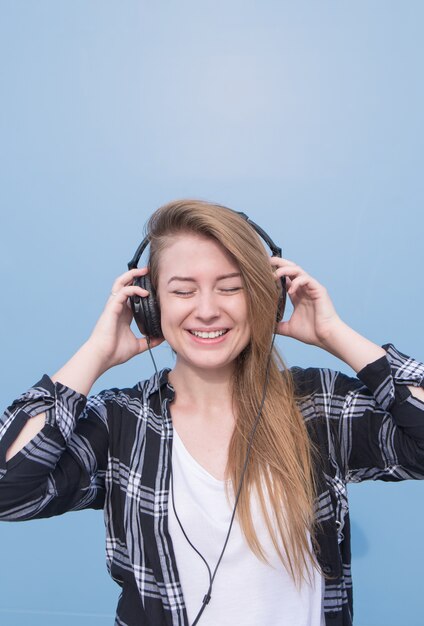 Student luistert naar muziek geïsoleerd op een blauwe achtergrond. Copyspace