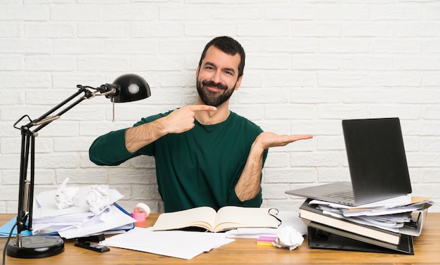 Student man holding copyspace imaginary on the palm to insert an ad