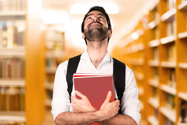 Student man looking up on defocused library