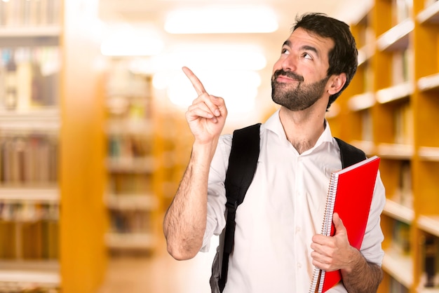 Student man thinking on defocused library