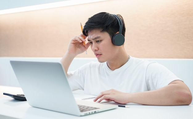 student man wearing headset and looking at laptop display for learning online course 