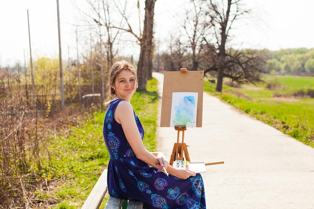Student meisje kunstenaar schilderij landschap in de open lucht in het vroege voorjaar Hobby en vrije tijd concept