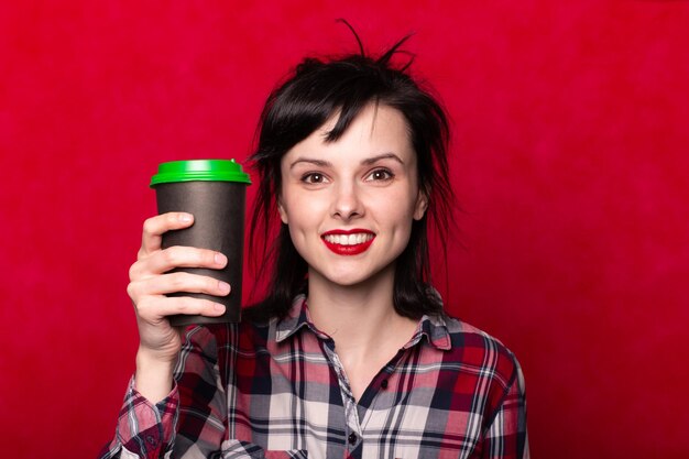 student meisje met een papieren kopje koffie rode achtergrond rode lippen