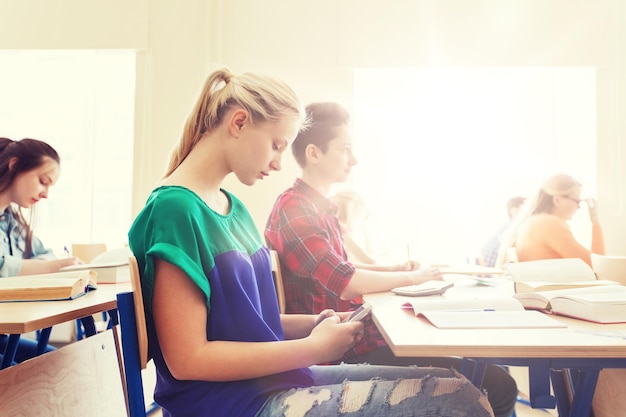 Foto student meisje met smartphone sms'en op school