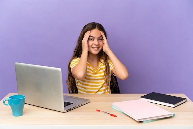 Student meisje op een werkplek met een laptop geïsoleerd op paarse achtergrond lachen