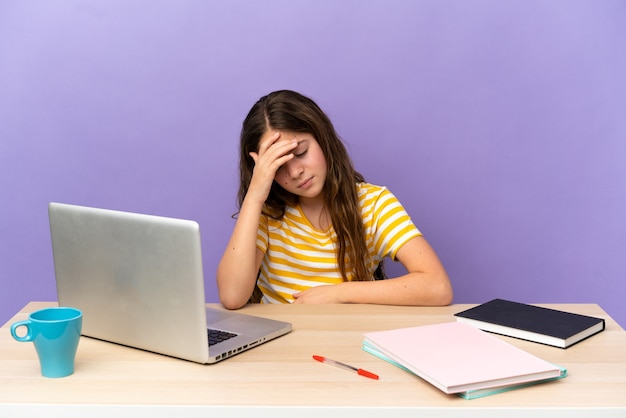 Student meisje op een werkplek met een laptop geïsoleerd op paarse achtergrond met hoofdpijn