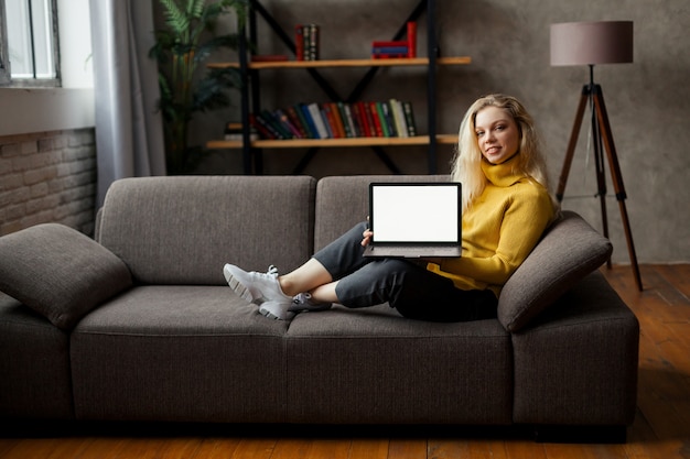 student meisje zit op de bank met laptop kijken naar mock-up scherm, online leren op pc, e learning. Close-up uitzicht