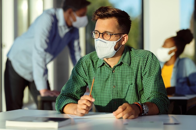 Student met gezichtsmasker die denkt tijdens een examen in de klas