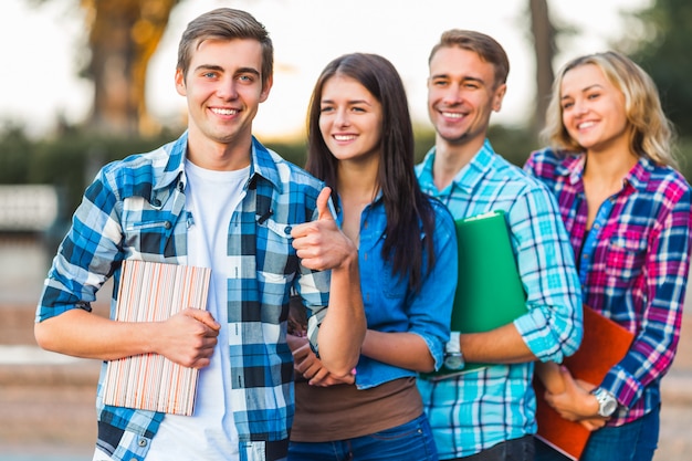 Student met handboeken in zijn handen die bevinden zich glimlachen.