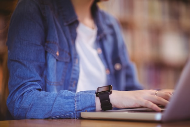 Student met smartwatch met laptop in de bibliotheek