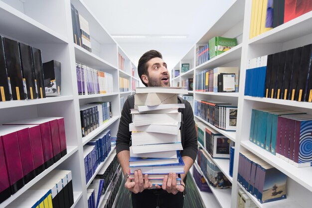 Student met veel boeken in de schoolbibliotheek Hardwerker en volhardend concept