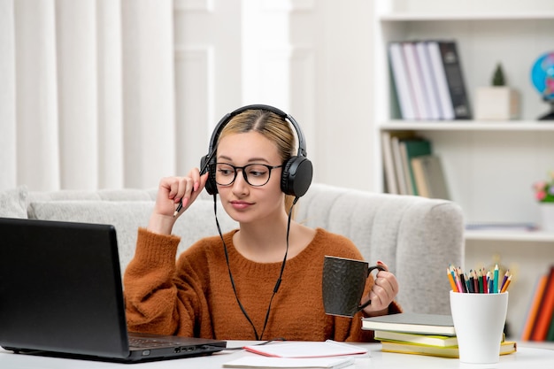 Student online cute girl in glasses and sweater studying on computer looking at screen