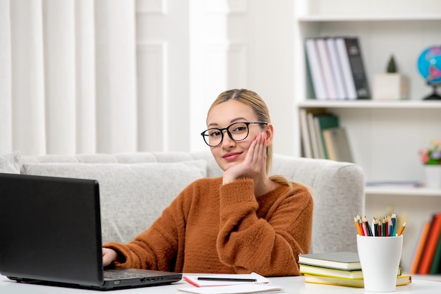 Student online jong schattig meisje in bril en oranje trui studeren op computer glimlachend