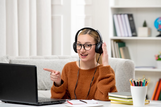 Student online jong schattig meisje in bril en oranje trui studeren op computer met koptelefoon