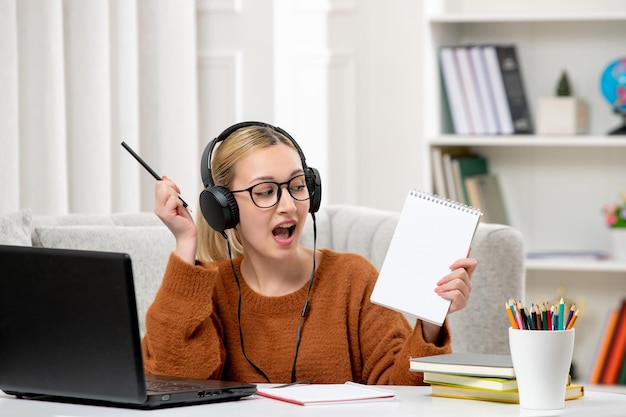 Student online schattig meisje in bril en trui studeren op computer blij met notities