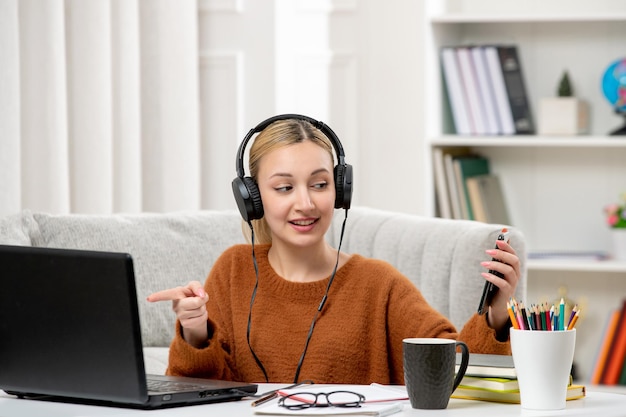 Student online schattig meisje in bril en trui studeren op computer met een telefoon