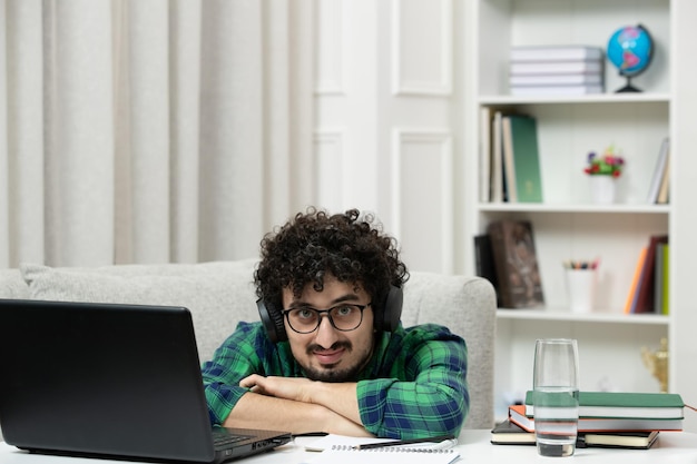 Student online schattige jonge kerel studeren op computer in bril in groen shirt met hoofd op bureau