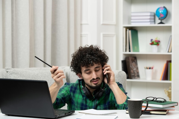 Student online schattige jonge kerel studeren op computer in glazen in groen shirt met pen