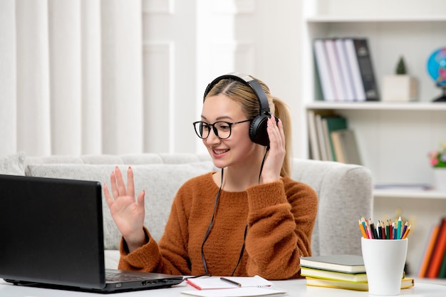 Photo student online young cute girl in glasses and orange sweater studying on computer happy