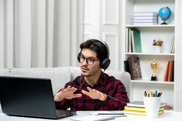 Student online young guy in checked shirt with glasses studying on computer talking on the video