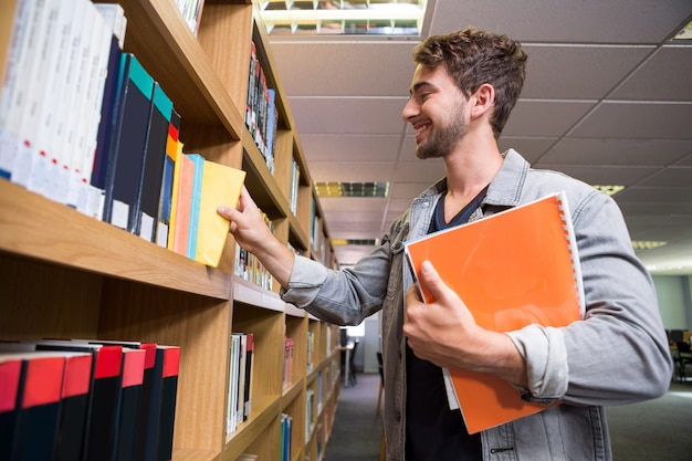 Student picking a book from shelf in library 