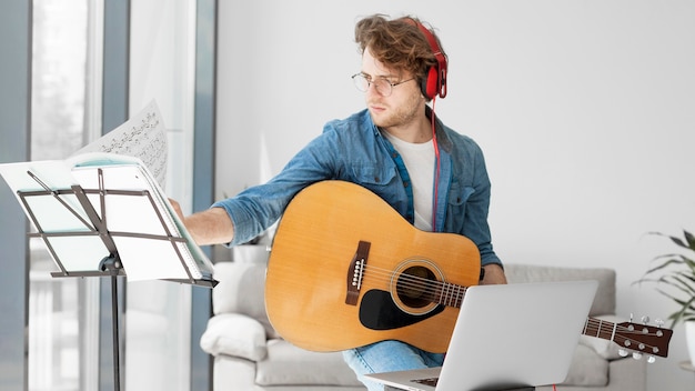 Foto studente a suonare la chitarra e indossare le cuffie