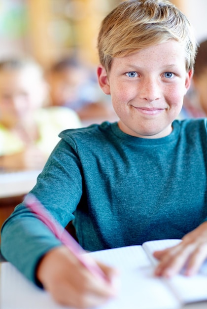 Foto ritratto di uno studente e appunti per l'apprendimento in classe ragazzo e risoluzione di problemi a scuola persona maschio bambino e informazioni di studio per la preparazione all'esame nel quaderno soluzione e giornale per la prova