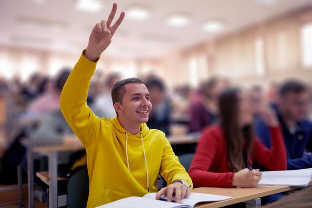 Photo the student raises his hands asking a question in class in college