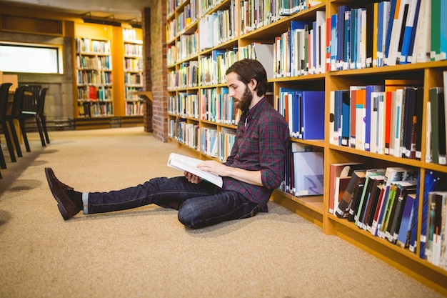 Student reading book in library on floor