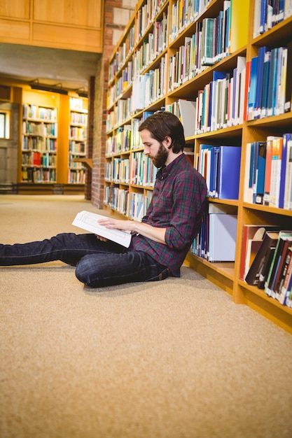 Student reading book in library on floor