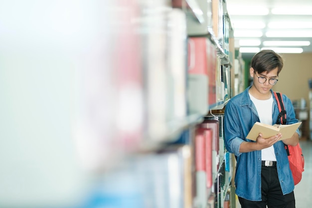 Studente che legge libro in biblioteca