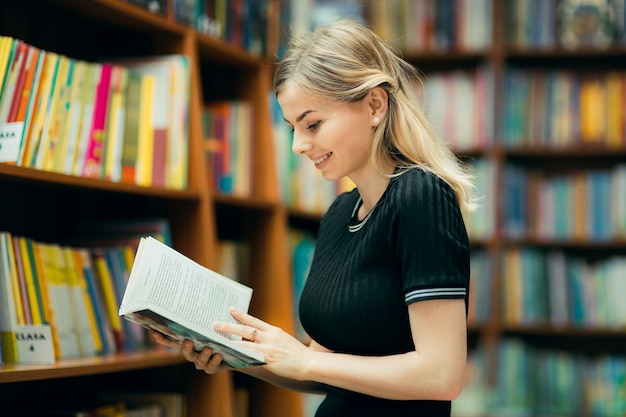 Studente che legge un libro in biblioteca