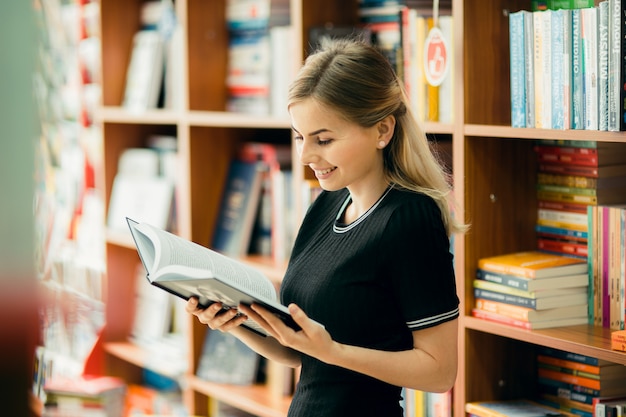 Foto studente che legge un libro in biblioteca