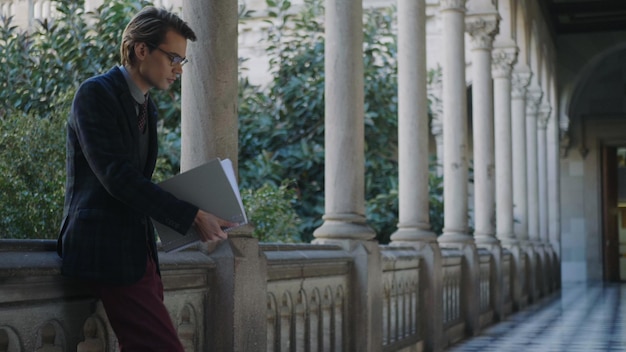 Student reading notes in workbook at university Businessman walking in hallway