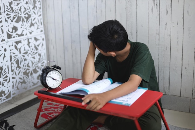 A student reads a book next to a clock that says'time is 10 : 00 '