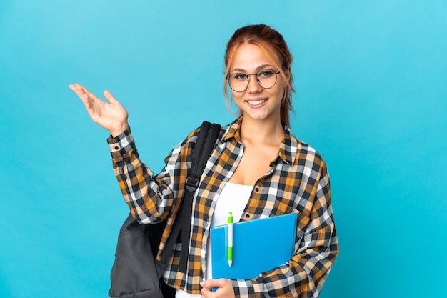 student Russian woman isolated on blue extending hands to the side for inviting to come