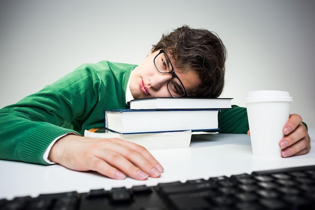 Foto student rustend hoofd op boeken