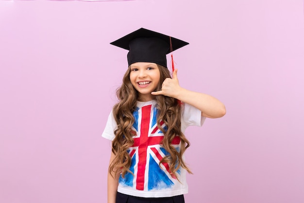 The student shows a hand gesture that she is calling on the phone. a schoolgirl with the flag of England on her T-shirt. a beautiful girl on an isolated pheolete background.