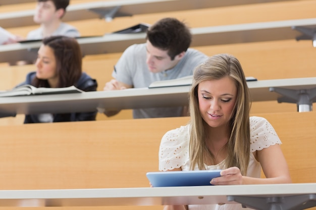 Студент, сидящий в лекционном зале с планшетным ПК