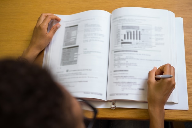 Foto studente seduto nella biblioteca di scrittura