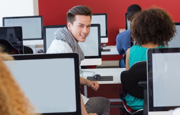 Foto studente che sorride alla macchina fotografica nella classe del computer