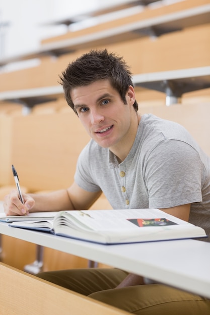 Foto studente sorridente mentre seduto e prendendo appunti