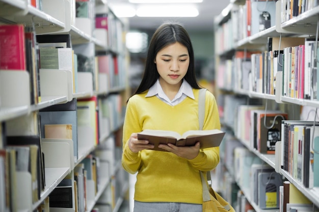 Student staande en leesboek in de bibliotheek