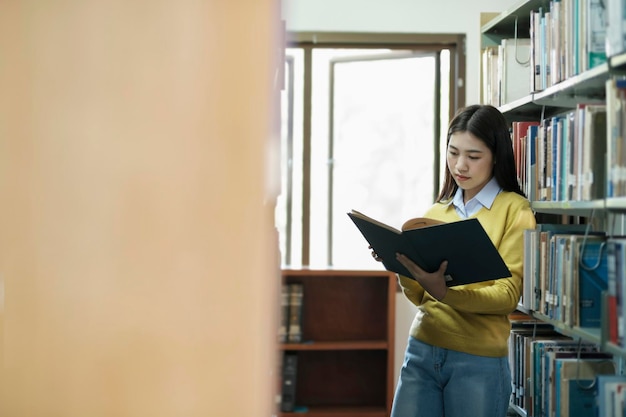 Student standing and reading book at library