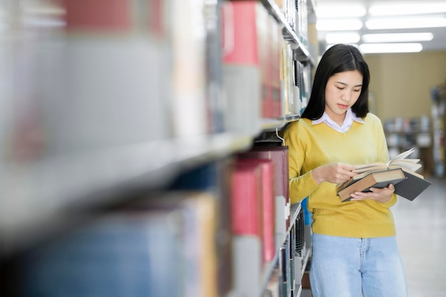 Student standing and reading book at library