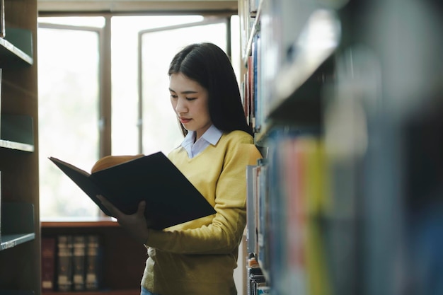 Студент стоит и читает книгу в библиотеке