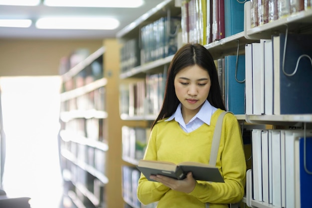 Student standing and reading book at library