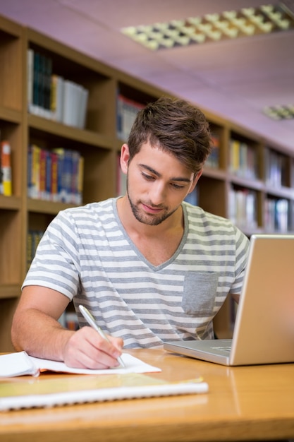 Student studeert in de bibliotheek met laptop