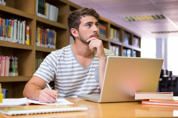 Student studeert in de bibliotheek met laptop